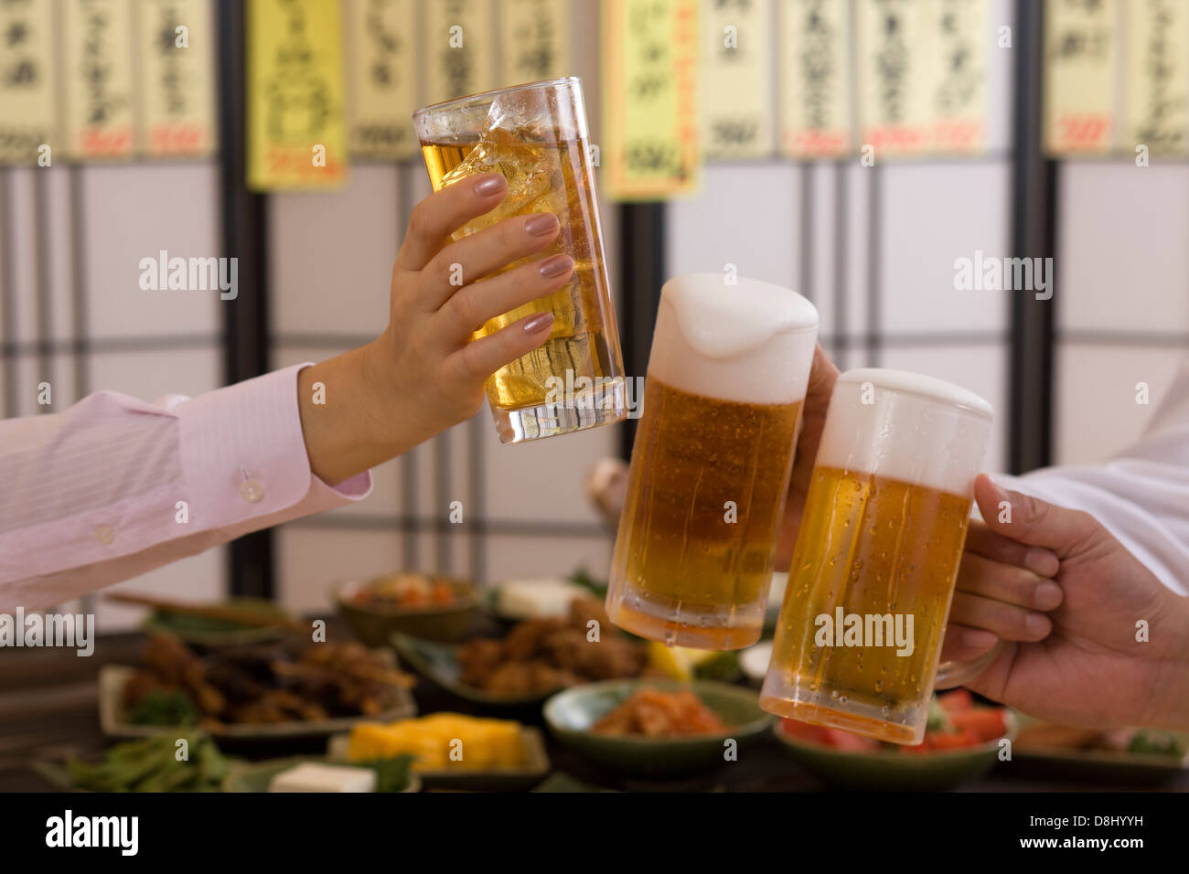 Tres personas con cerveza y tostado en Izakaya Chu-Hi Foto de stock