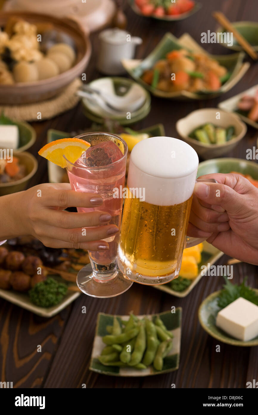 Dos personas brindando con cerveza y Cocktail en Izakaya Foto de stock