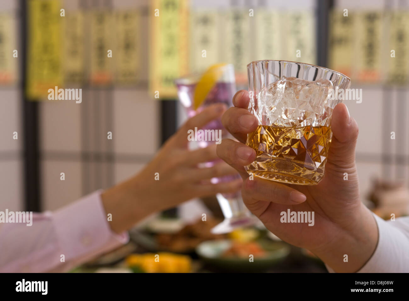 Dos personas brindando con Whisky y cóctel en Izakaya Foto de stock