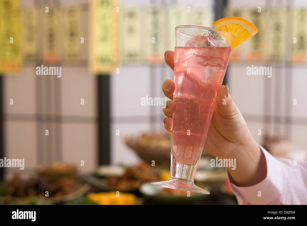 Mano humana sosteniendo una copa de cóctel en Izakaya Foto de stock
