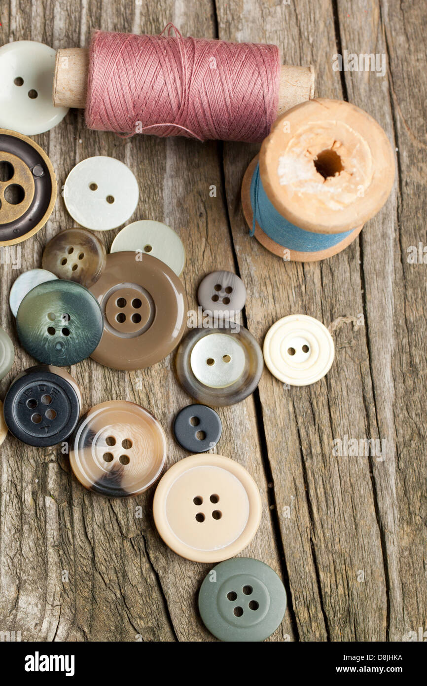 Carretes de hilos y botones en la mesa de madera antigua Foto de stock