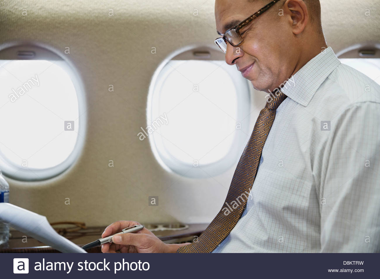 Empresario leer documentos en avión Foto de stock