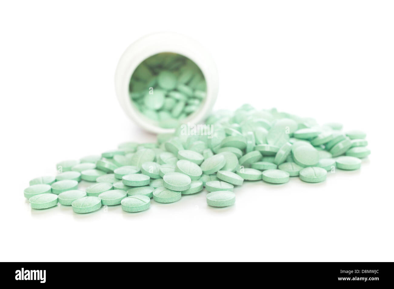 Los medicamentos recetados - tabletas verde derramándose de un plástico blanco botella de prescripción. DOF superficial, centrarse en primer plano. Foto de stock