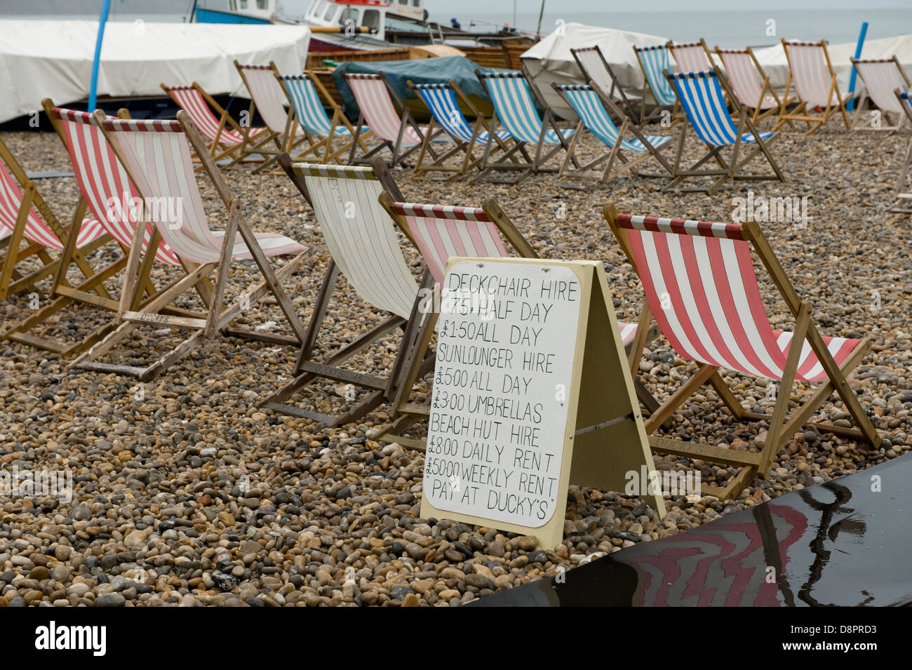 Desocupado tumbonas y aviso en un húmedo día de verano en la playa de cerveza en Devon Foto de stock