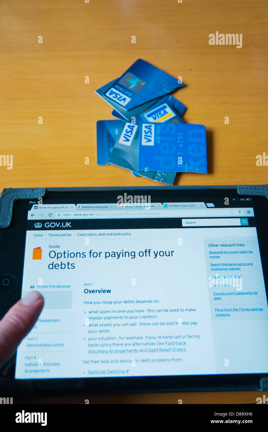 Persona mirando hacia el alivio de la deuda en el Reino Unido información sobre internet en el ipad mini tablet PC en casa Foto de stock
