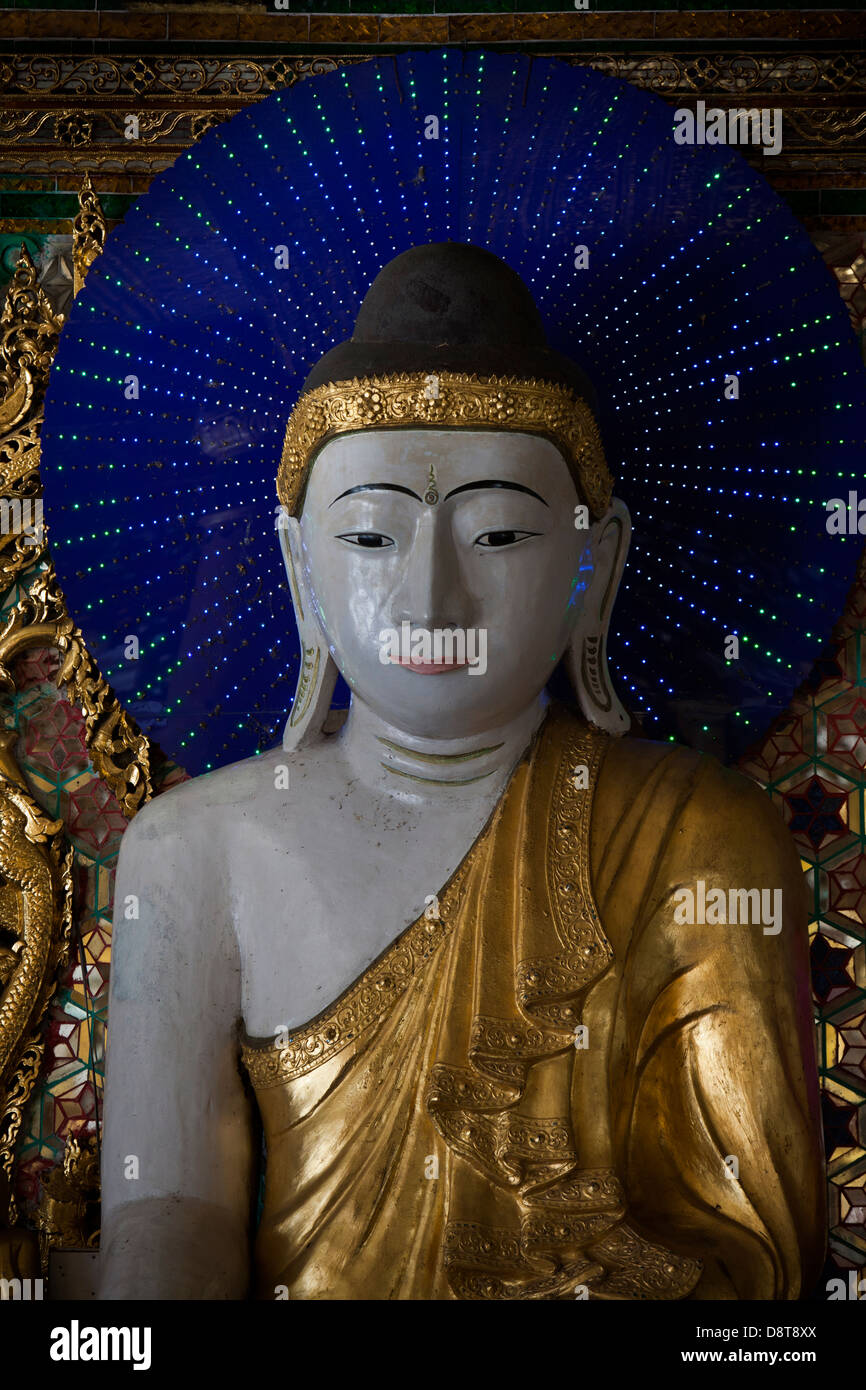 Muchas figuras de Buddha en las capillas laterales en el templo Schwedagon tienen halos de color azul con luces parpadeantes hacer patrones. Foto de stock