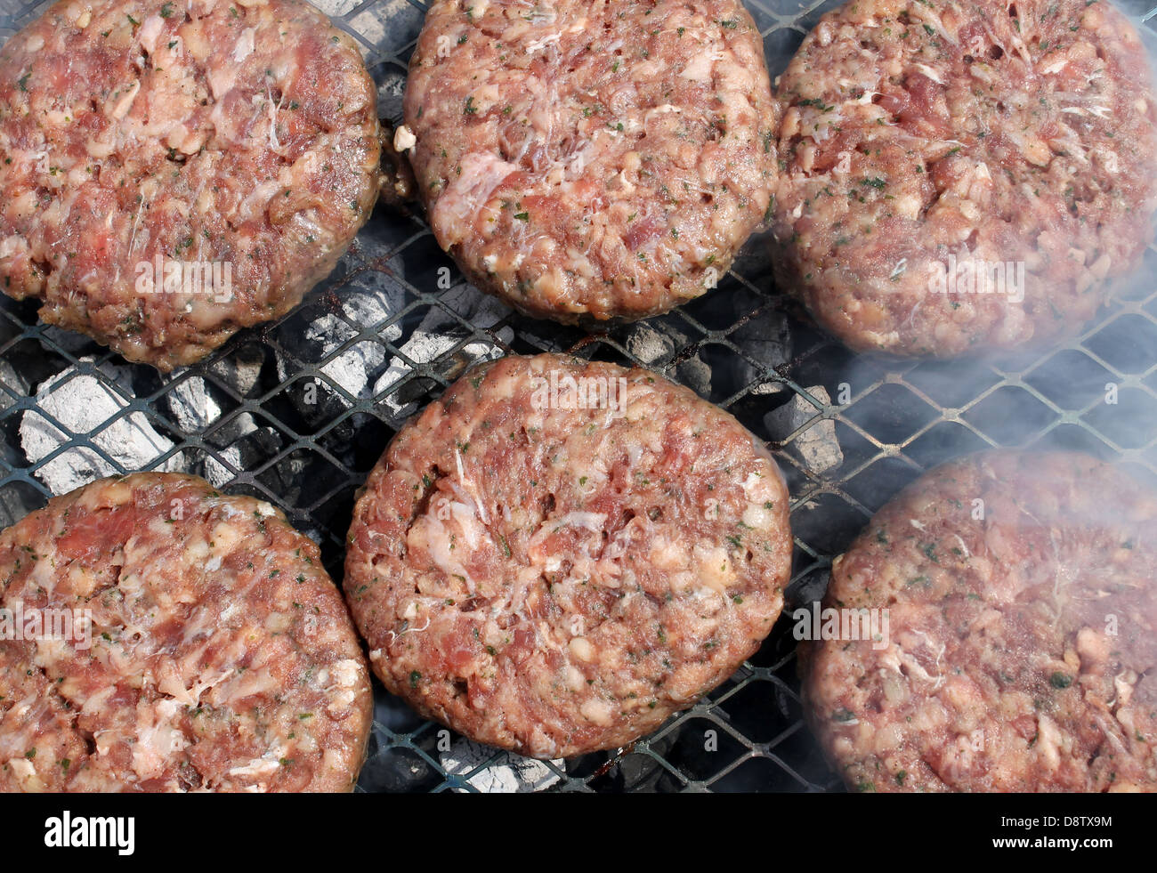 Cocinar hamburguesas de carne roja en la parrilla al aire libre. Foto de stock