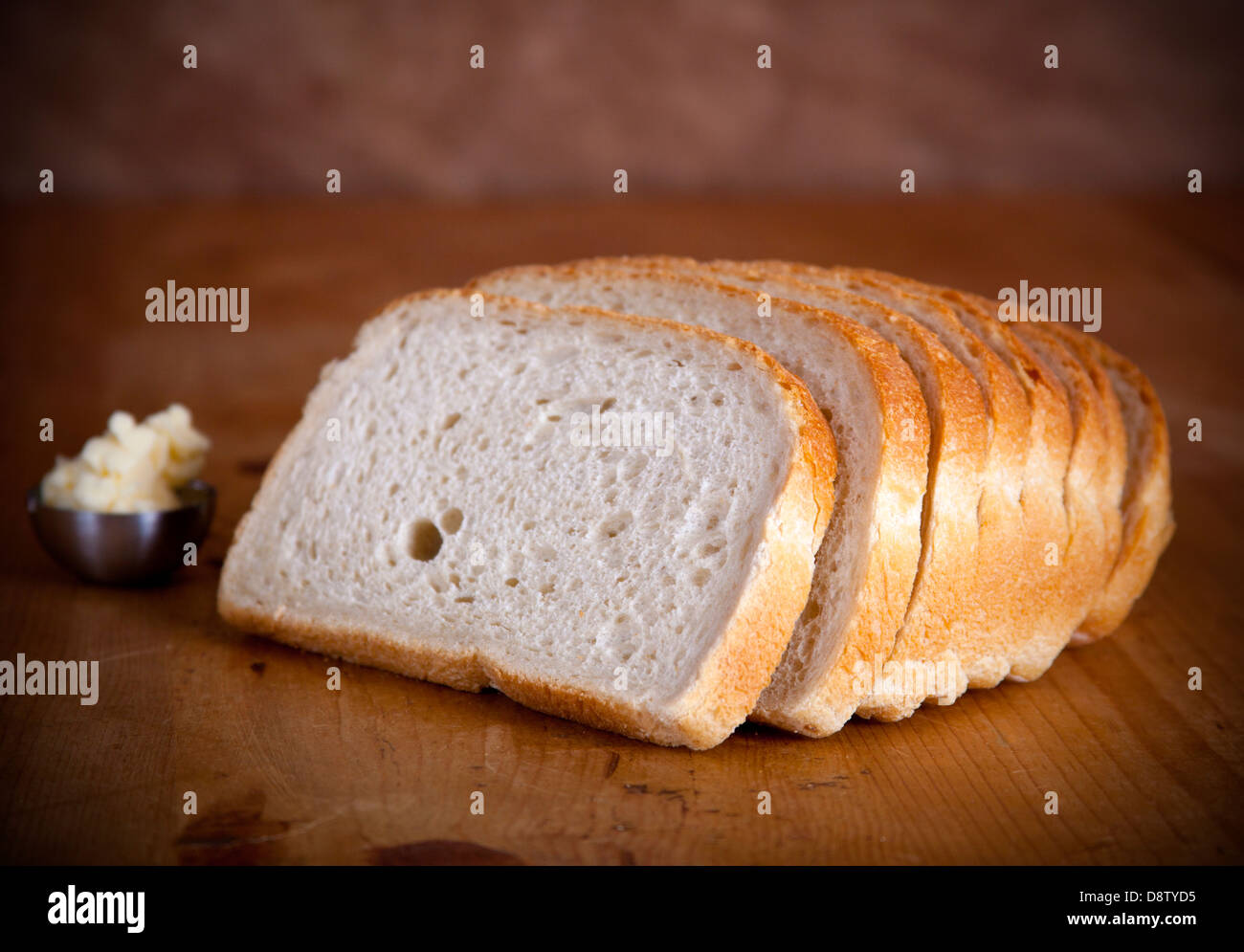 Rebanadas de pan fresco en una mesa de madera con mantequilla Foto de stock