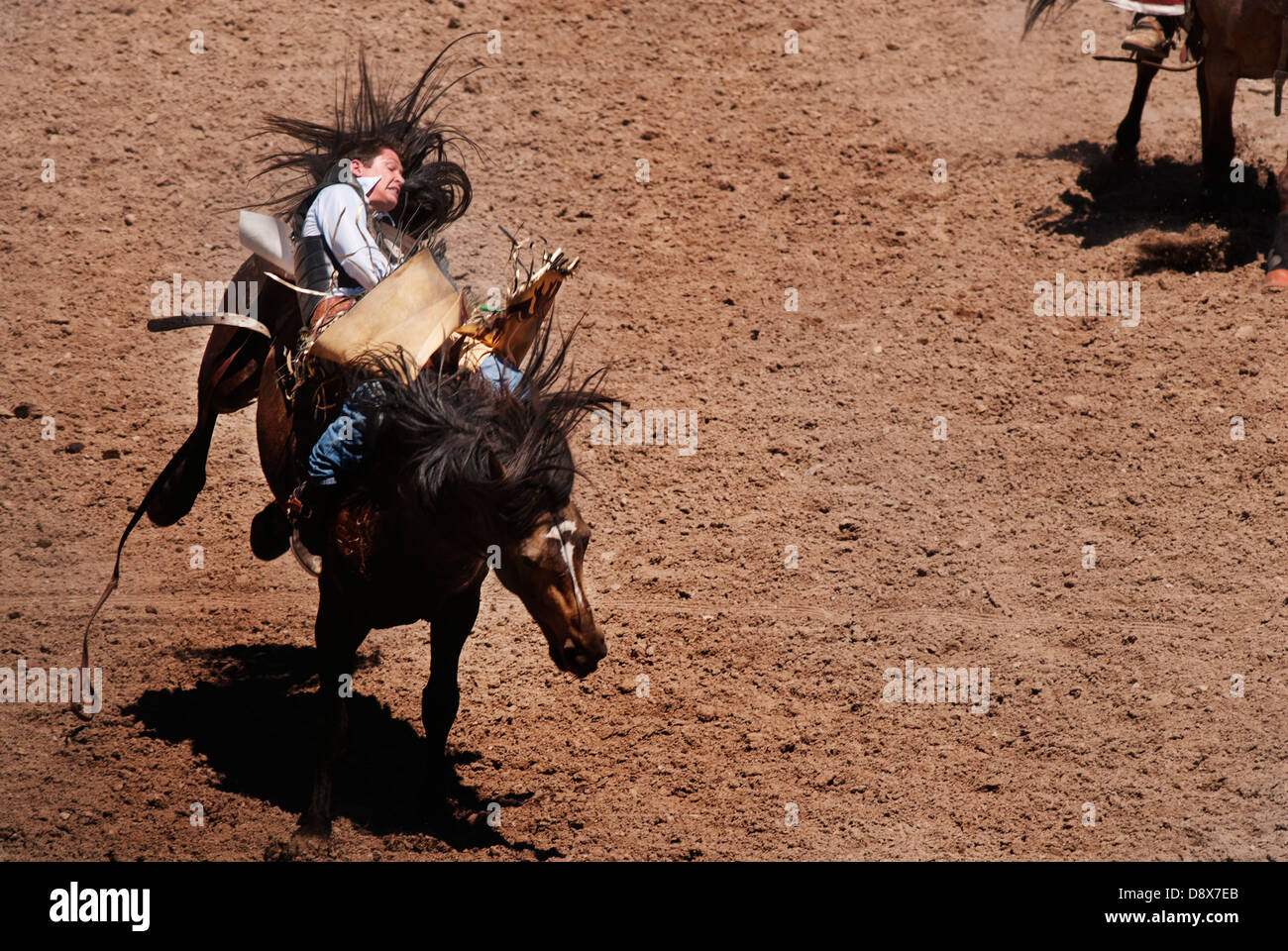 Cowboys montando caballos bronco en una competencia de rodeo Foto de stock