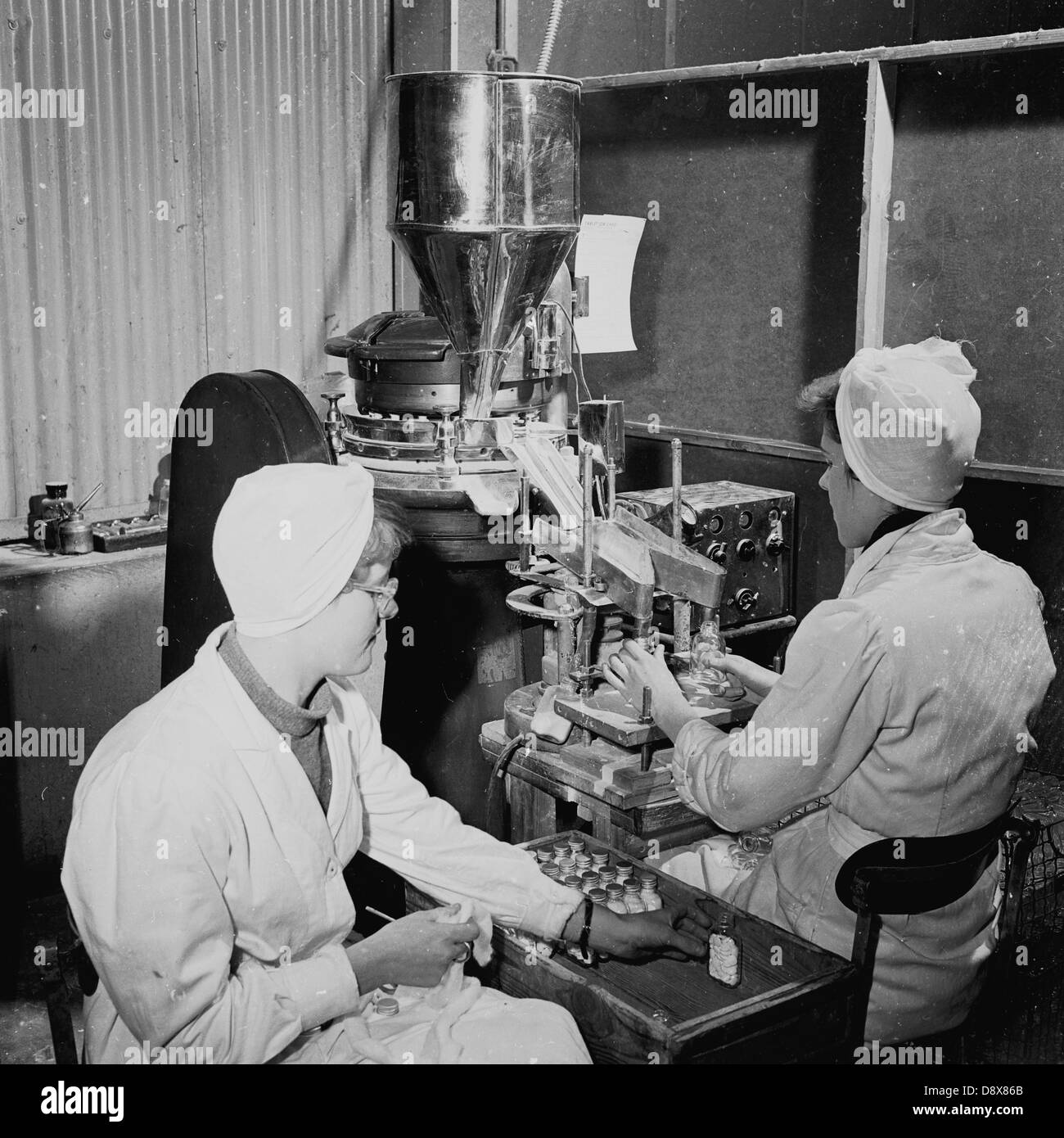 Histórico de 1950. Inglaterra. medicamentos. Las mujeres que trabajan en las fábricas con una máquina para poner tapas en frascos de píldoras o tabletas. Foto de stock