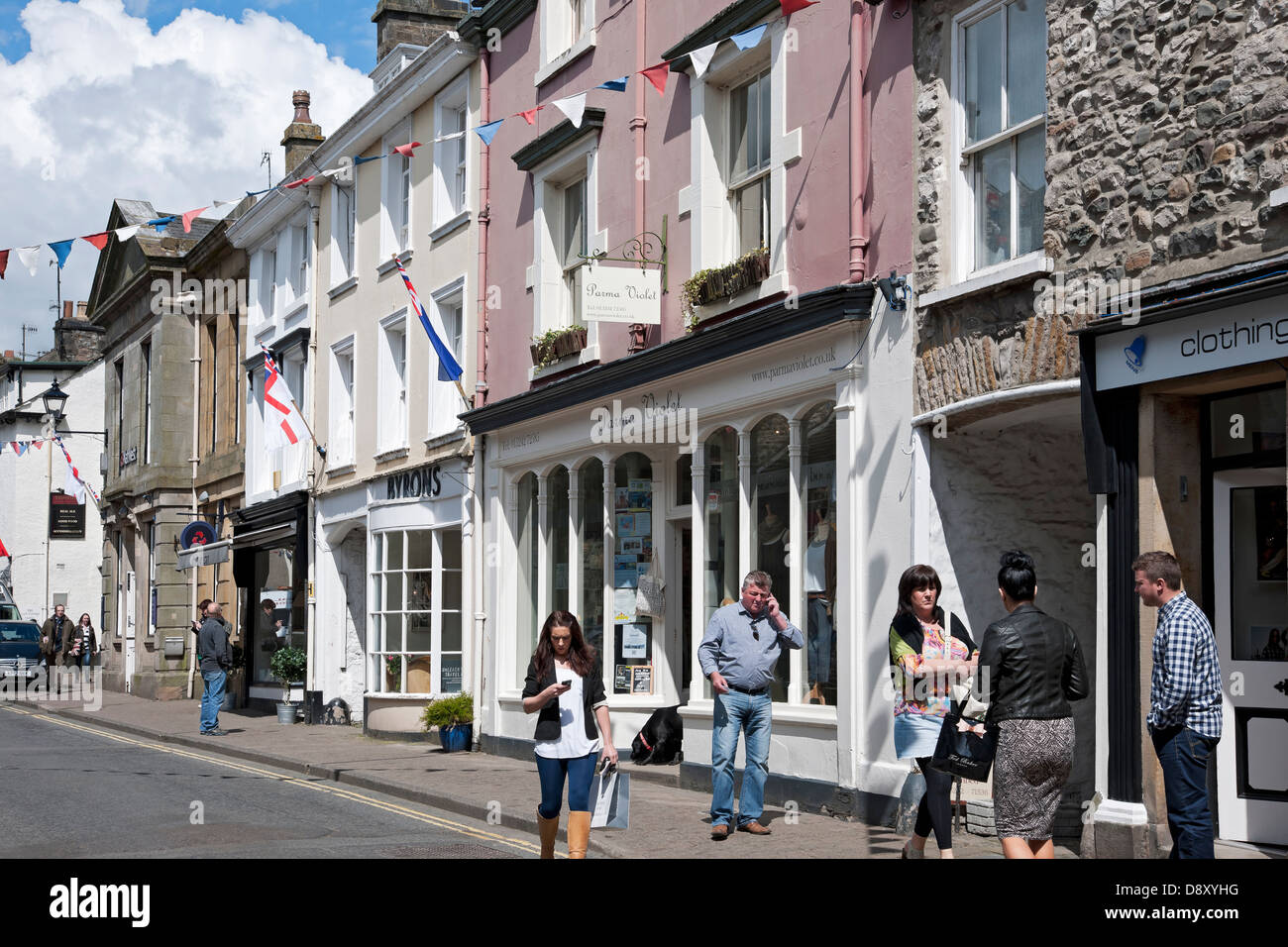 Gente turistas visitantes fuera Tiendas tiendas negocios en la calle principal Kirkby Lonsdale Cumbria Inglaterra Reino Unido Gran Bretaña Foto de stock