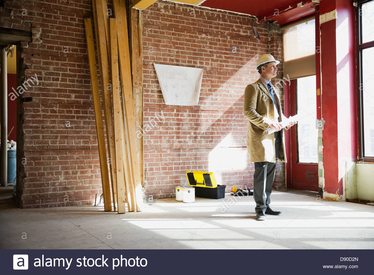 Arquitecto masculino con Blueprint de pie al sitio en construcción Foto de stock