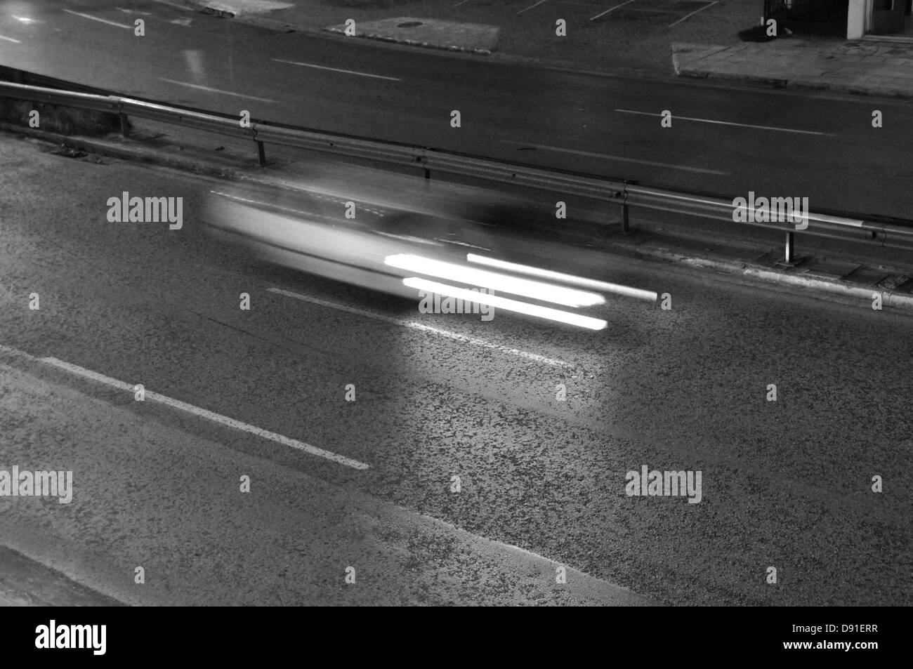 Acelerar el coche por la autopista el tráfico en la ciudad por la noche. Desenfoque de movimiento, el negro y el blanco. Foto de stock