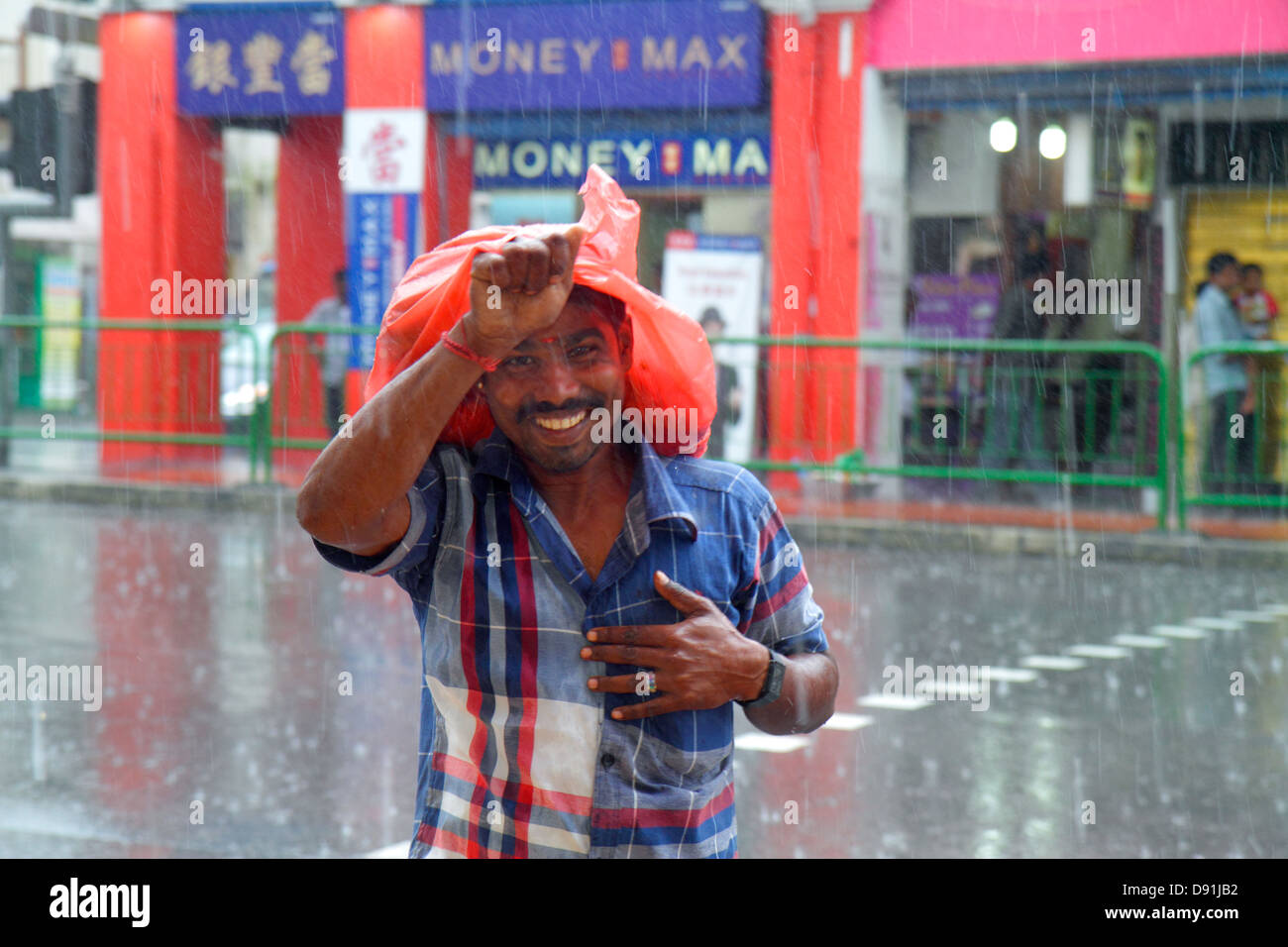 Singapur Little India,Serangoon Road,hombre asiático masculino,correr,lluvia,llover,clima,monzón,más,cabeza,cubrir,Sing130203088 Foto de stock