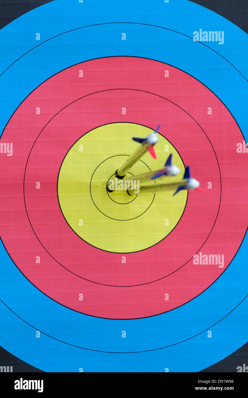 Tres flechas incrustadas en el centro muerto de un tiro con arco facial centrarse en el objetivo de destino Foto de stock