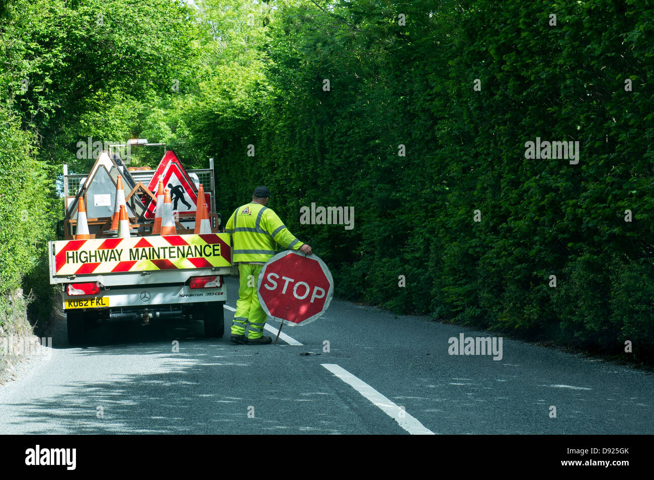 Los trabajadores de mantenimiento de carreteras la celebración de una señal de tráfico de STOP. Devon, Inglaterra Foto de stock
