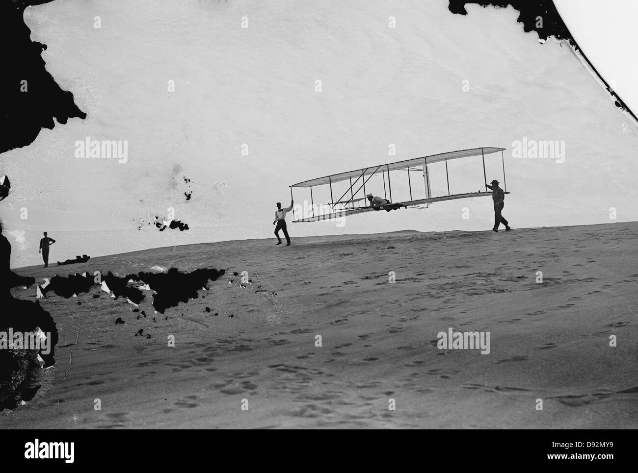 Inicio de GLIDE, Wilbur Wright en movimiento a la izquierda sostienen el extremo de planeadores Orville Wright tumbado prono en la máquina (foto está dañado). Foto de stock