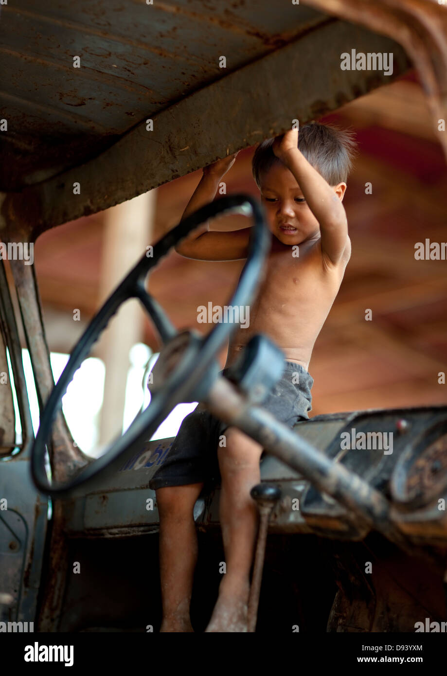 Niño jugando en un viejo coche, Thakhek, Laos Foto de stock