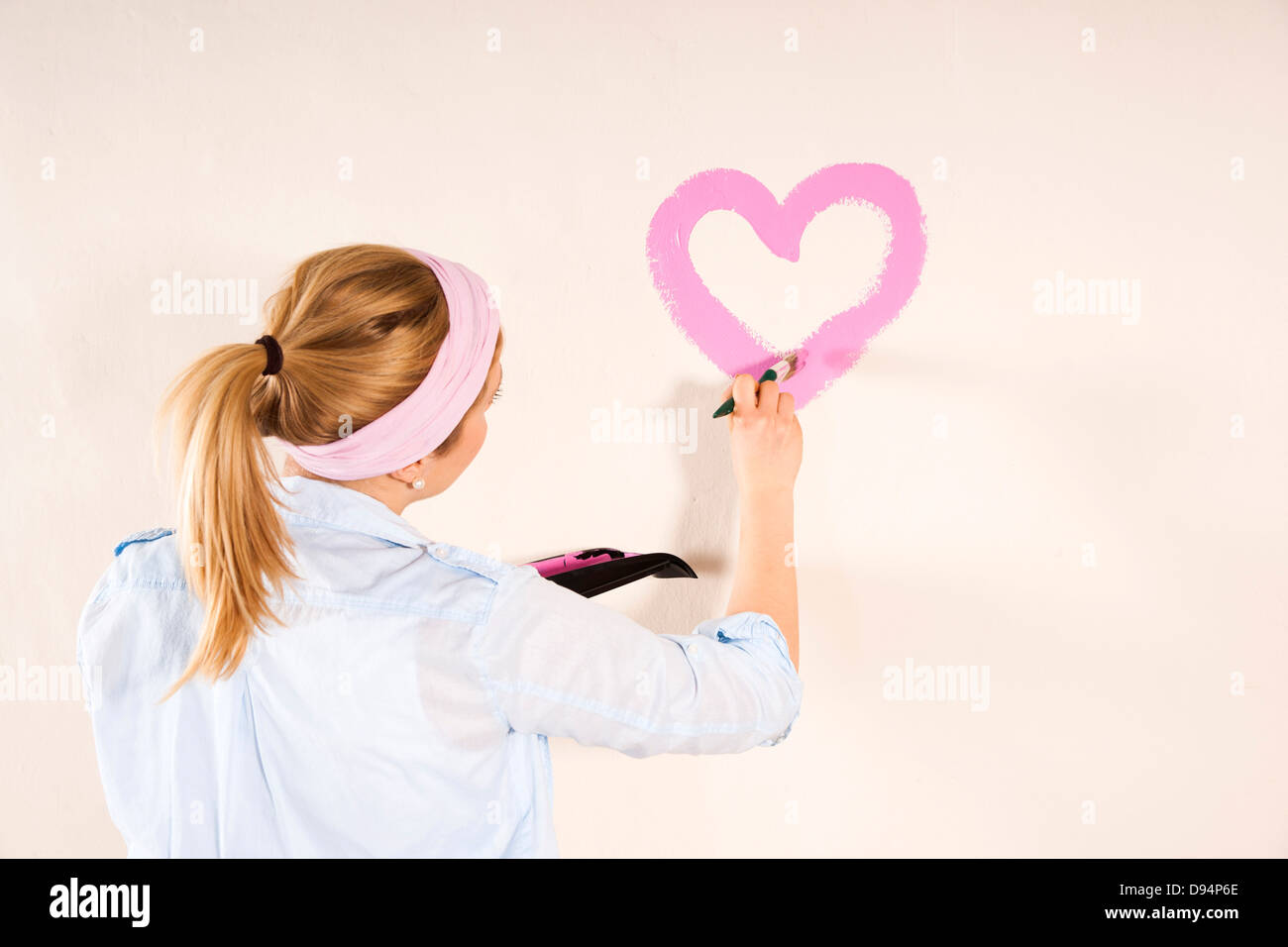 Foto de estudio de joven corazón de pintura en la pared Foto de stock