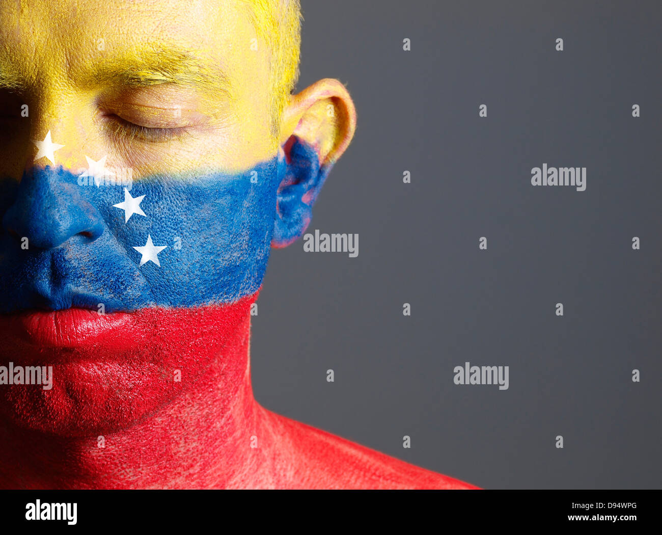 El hombre y su cara pintada con la bandera de Venezuela. El hombre tiene sus ojos cerrados y composición fotográfica deja sólo la mitad de th Foto de stock