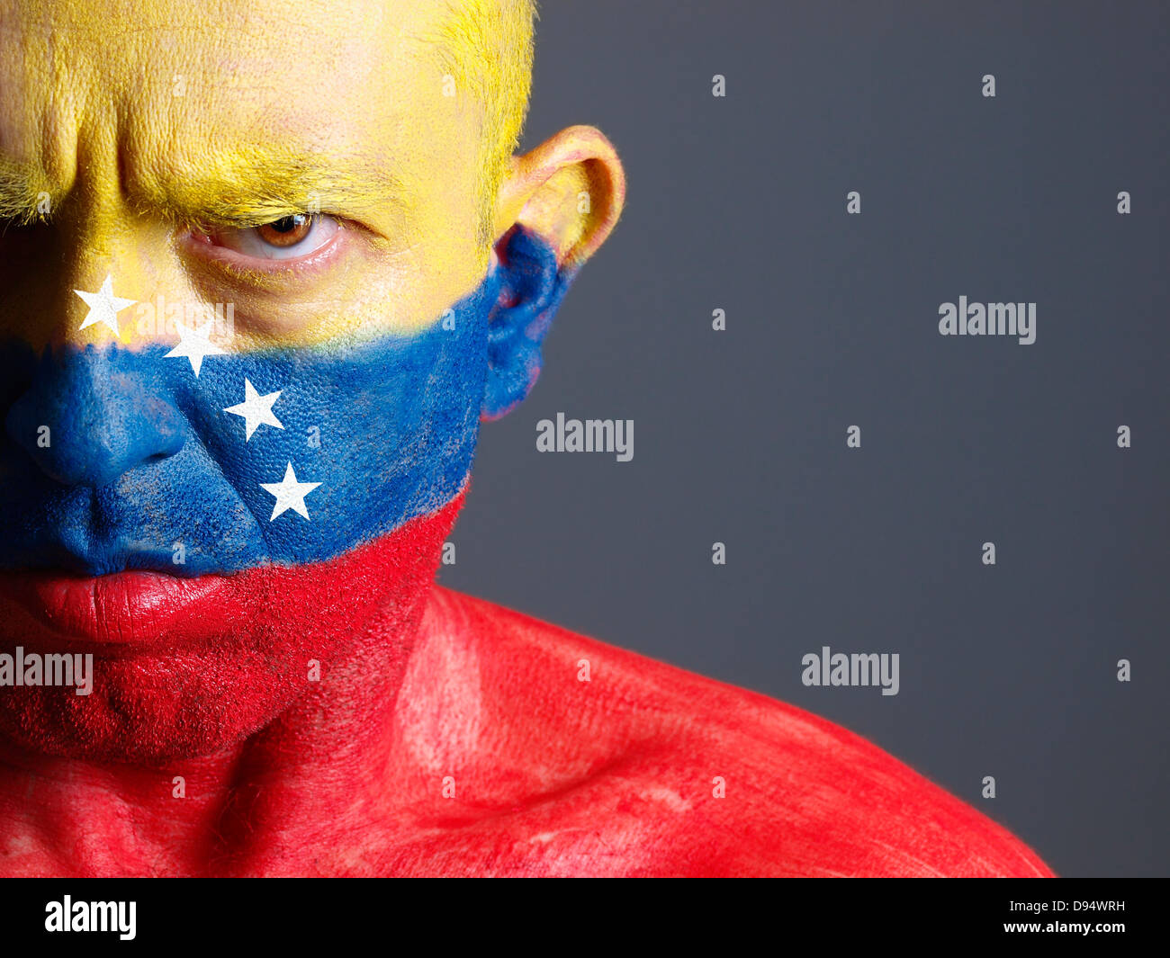 El hombre y su cara pintada con la bandera de Venezuela. El hombre es grave y composición fotográfica deja sólo la mitad de la FAC Foto de stock