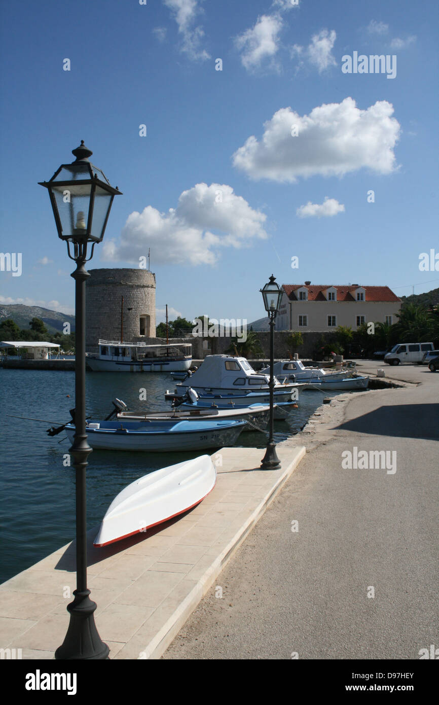 Retrato de Mali Ston Harbour Side Dubrovnik Croacia Europa. Día soleado con nubes de luz a través de pequeñas embarcaciones, tradicional farola Foto de stock