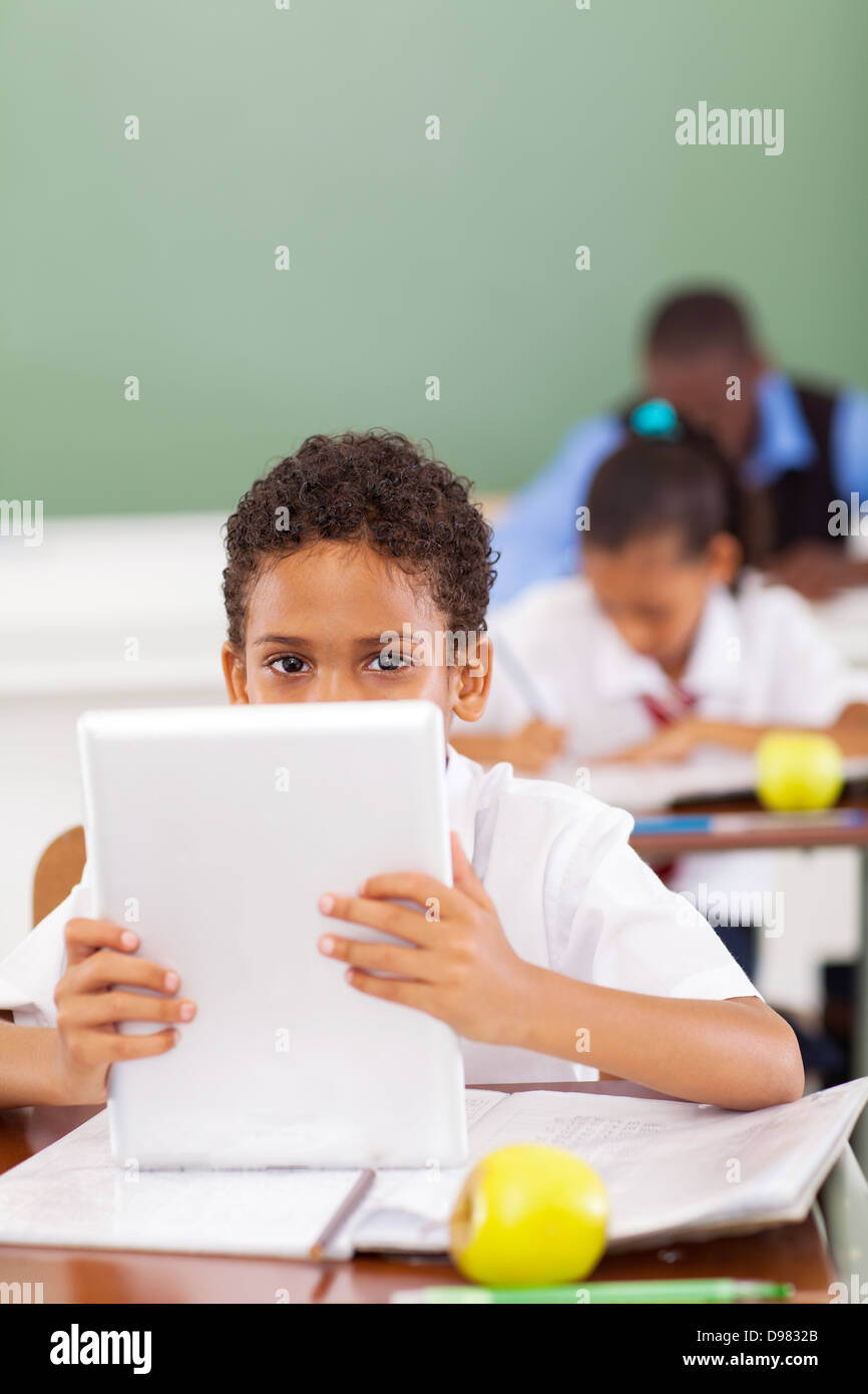 Alumno de la escuela elemental lindo con tablet PC en el aula Foto de stock