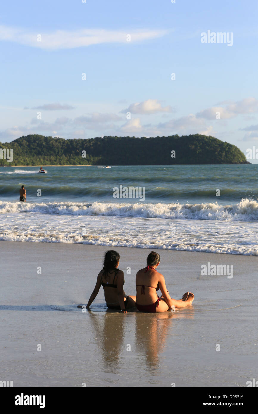 Dos jóvenes turistas occidentales relajándose en la playa (playa de Pantai Cenang) en la isla de Langkawi, Malasia Foto de stock