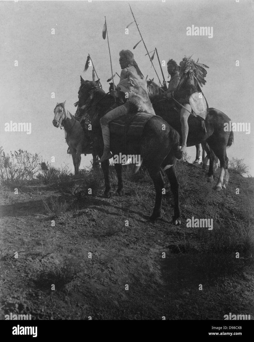 Cuatro hombres a caballo Cuervo sosteniendo lanzas con plumas, c1910. Fotografía por Edward Curtis (1868-1952). Foto de stock
