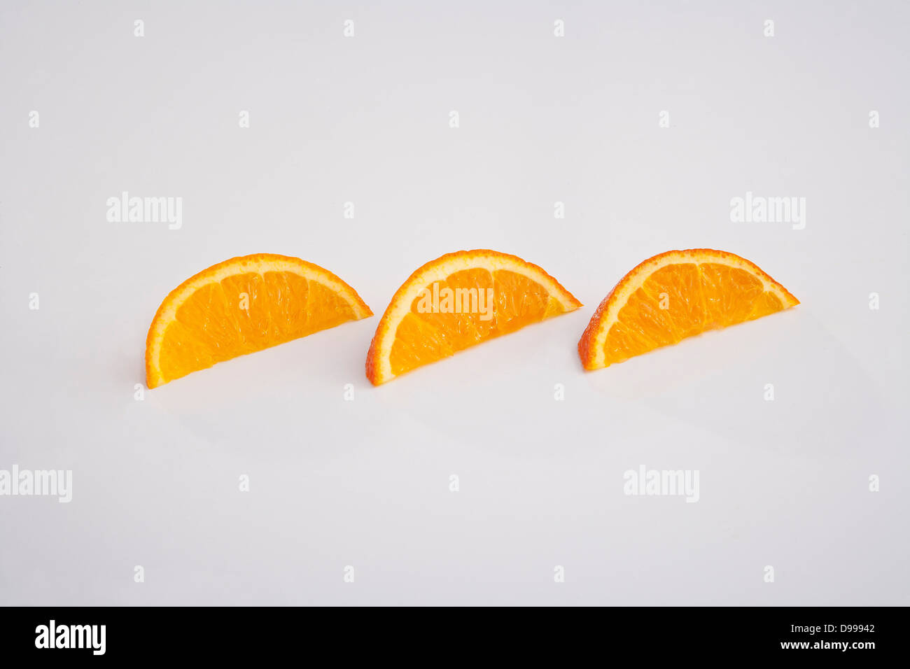 Tres gajos de naranja y secciones en blanco Foto de stock