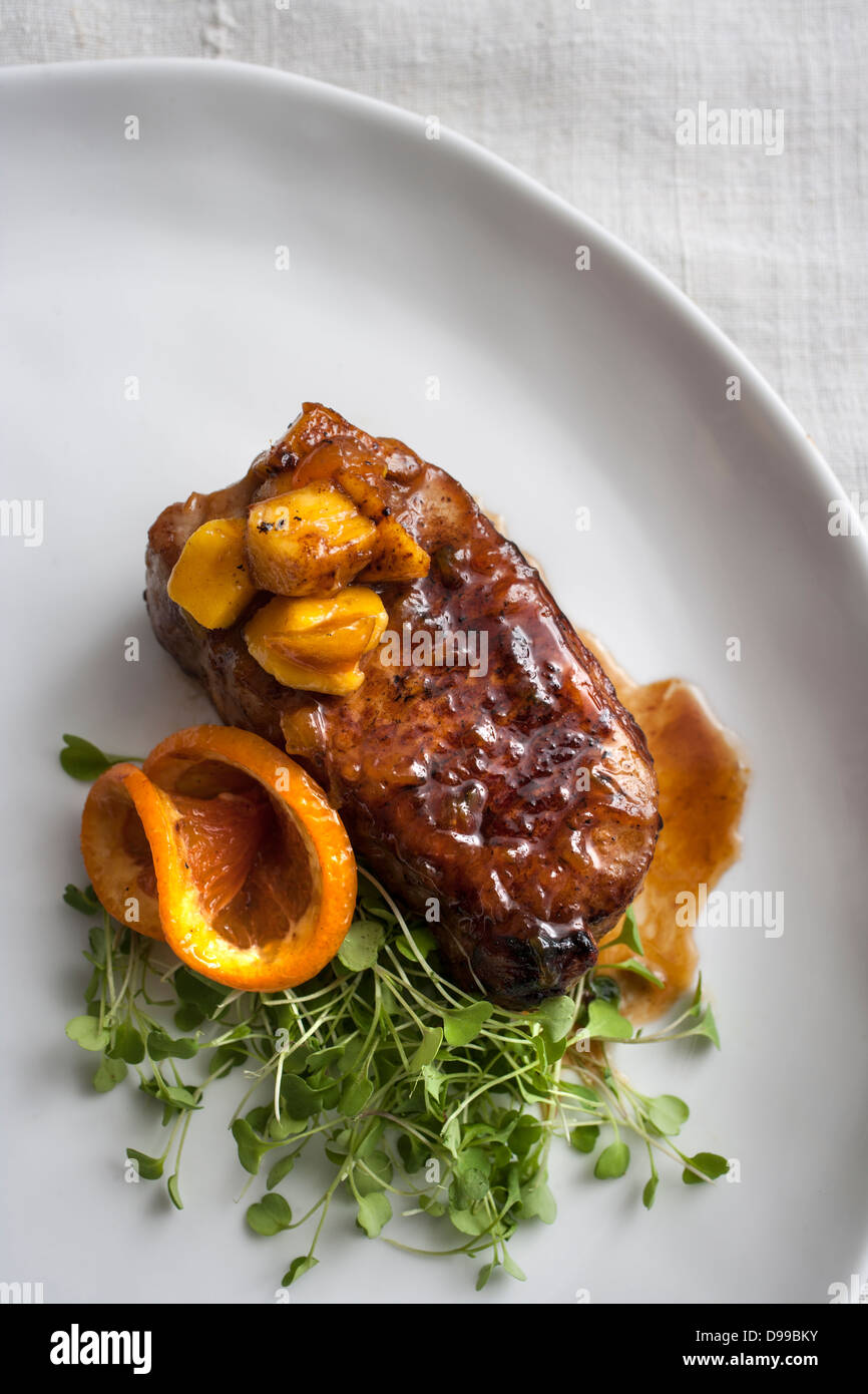 Lomo de cerdo con salsa de mango y brotes de naranja Foto de stock