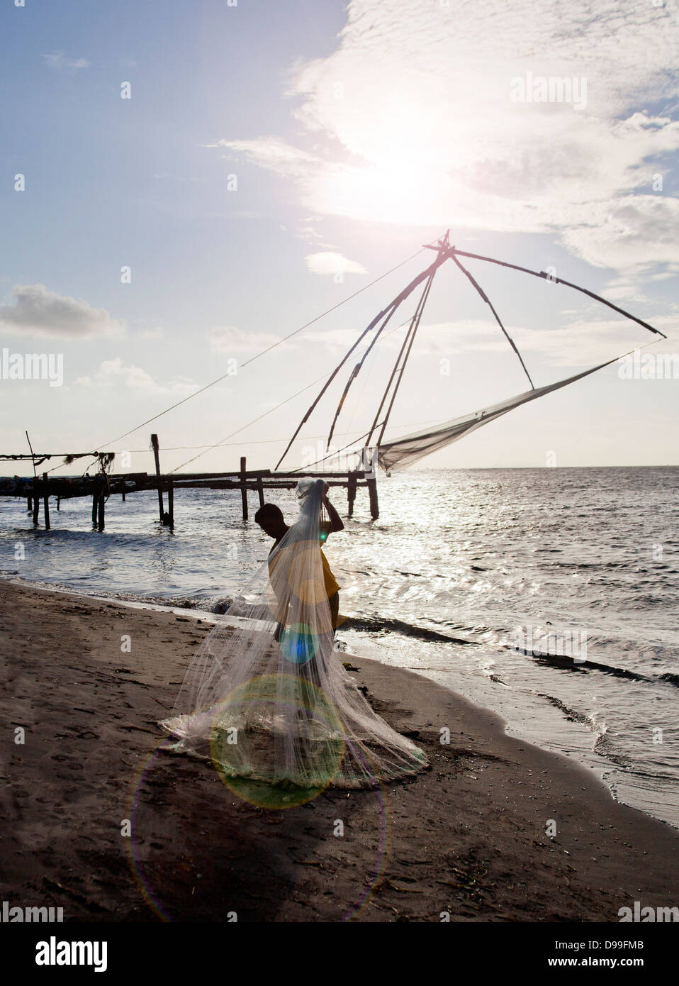 Pescador mantiene una red de pesca en la playa, Cochin, Kerala, India Foto de stock