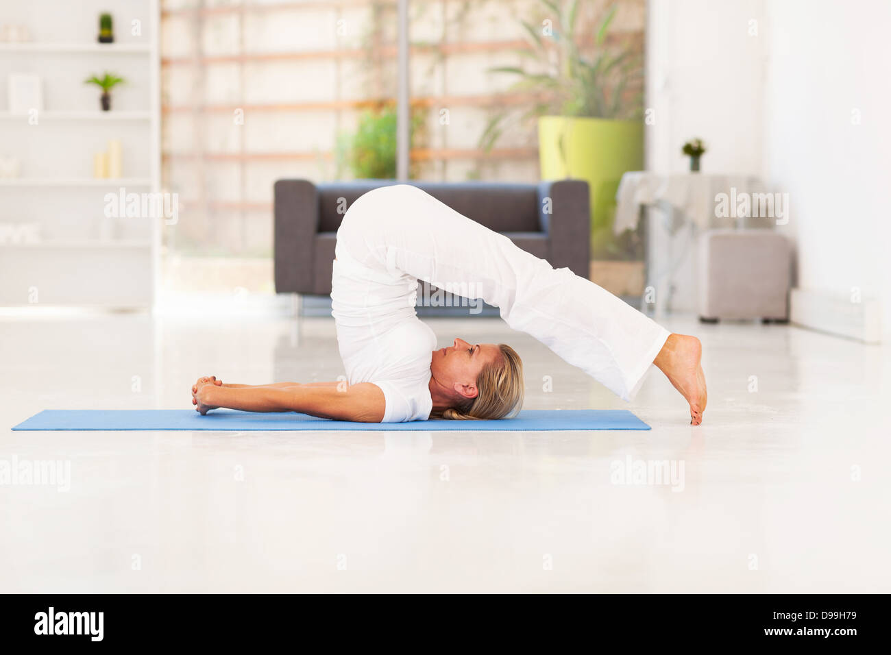 Señora de mediana edad hacer yoga en casa Foto de stock
