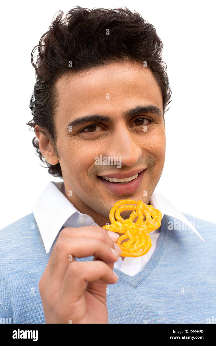 Retrato de un hombre comiendo jalebi sonriente Foto de stock
