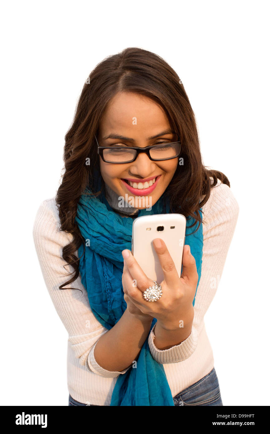 Mujer sonriente mensajería de texto con un teléfono móvil Foto de stock