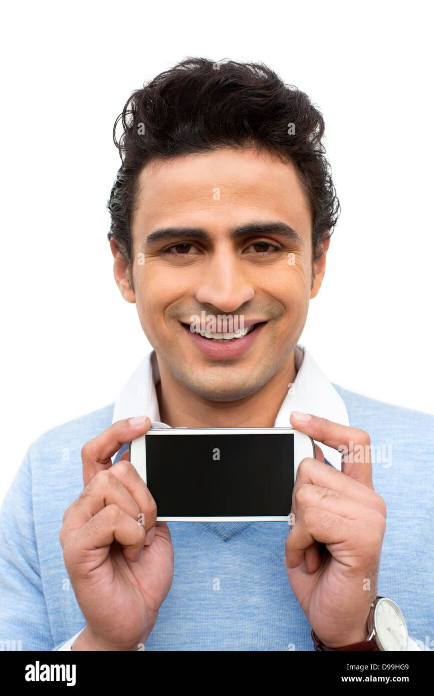 Retrato de un hombre mostrando un teléfono móvil y sonriendo Foto de stock