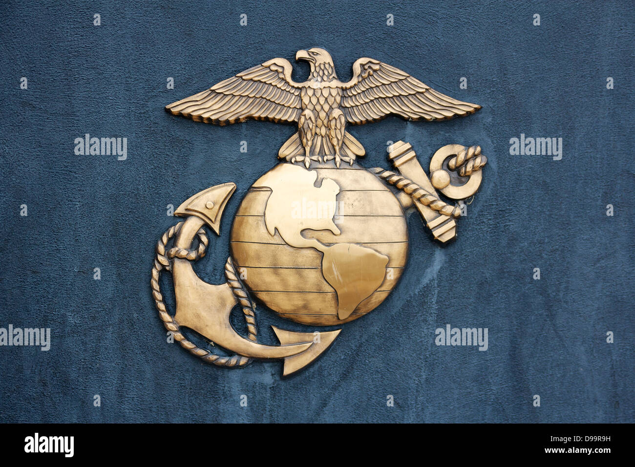 Insignia de la Infantería de Marina de Estados Unidos en golden metal bruñido en una pared gris-azul oscuro. Foto de stock