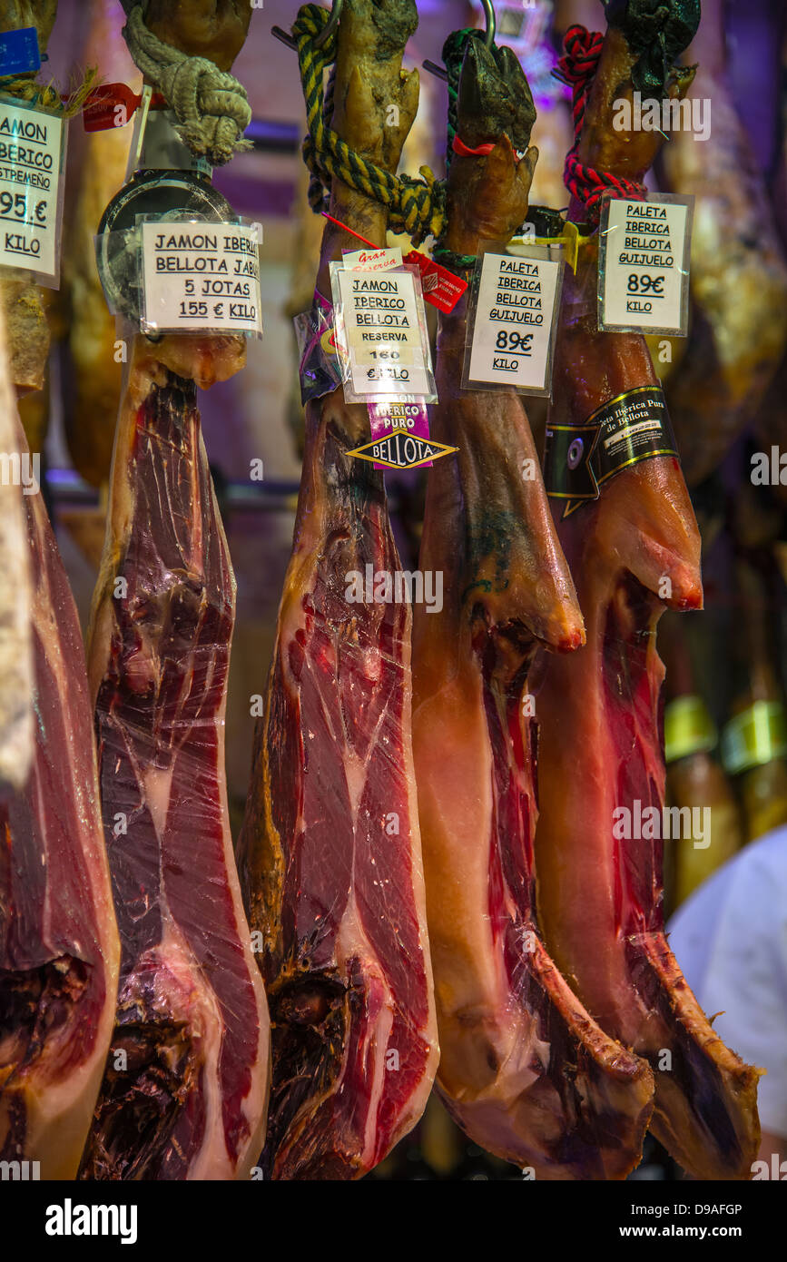 Español jamones colgando en el mercado de La Boqueria, Barcelona, Cataluña, España Foto de stock