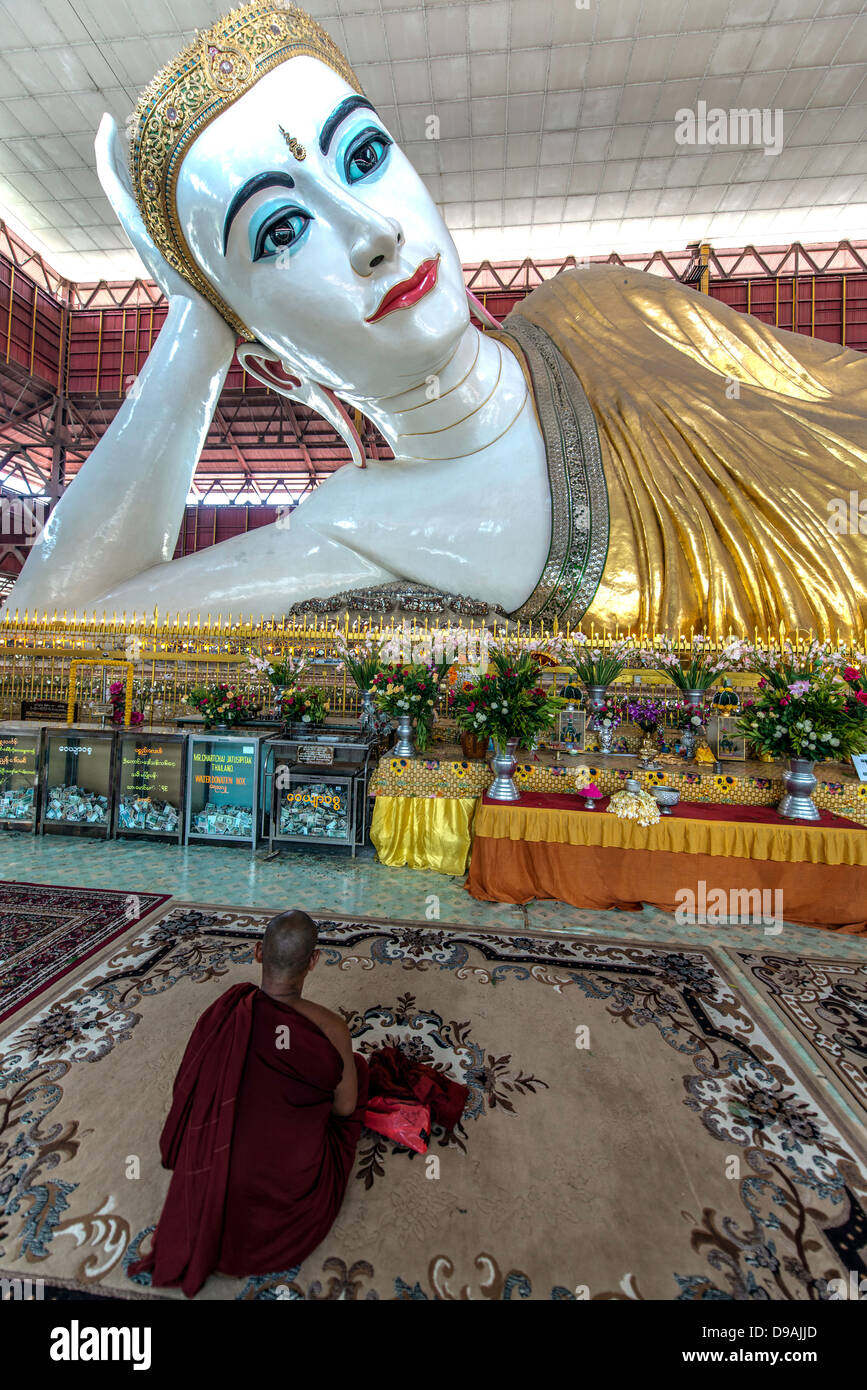 Monje orando por la gigantesca estatua de Buda reclinado Chaukhtatgyi Paya Rangún Birmania Myanmar Foto de stock