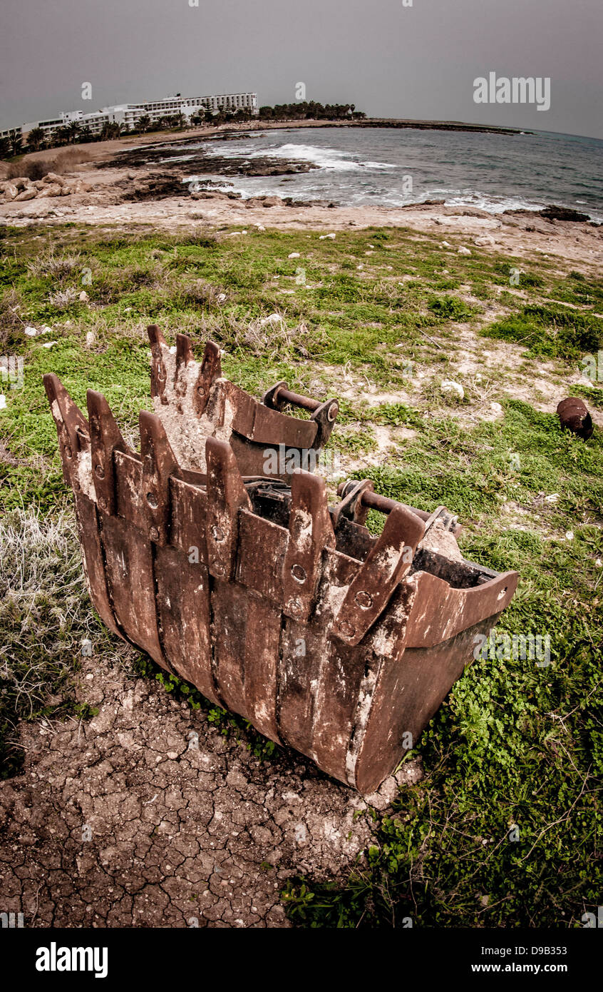 Rusty digger el cucharón en la playa en proyecto de construcción abandonados, Chipre Foto de stock