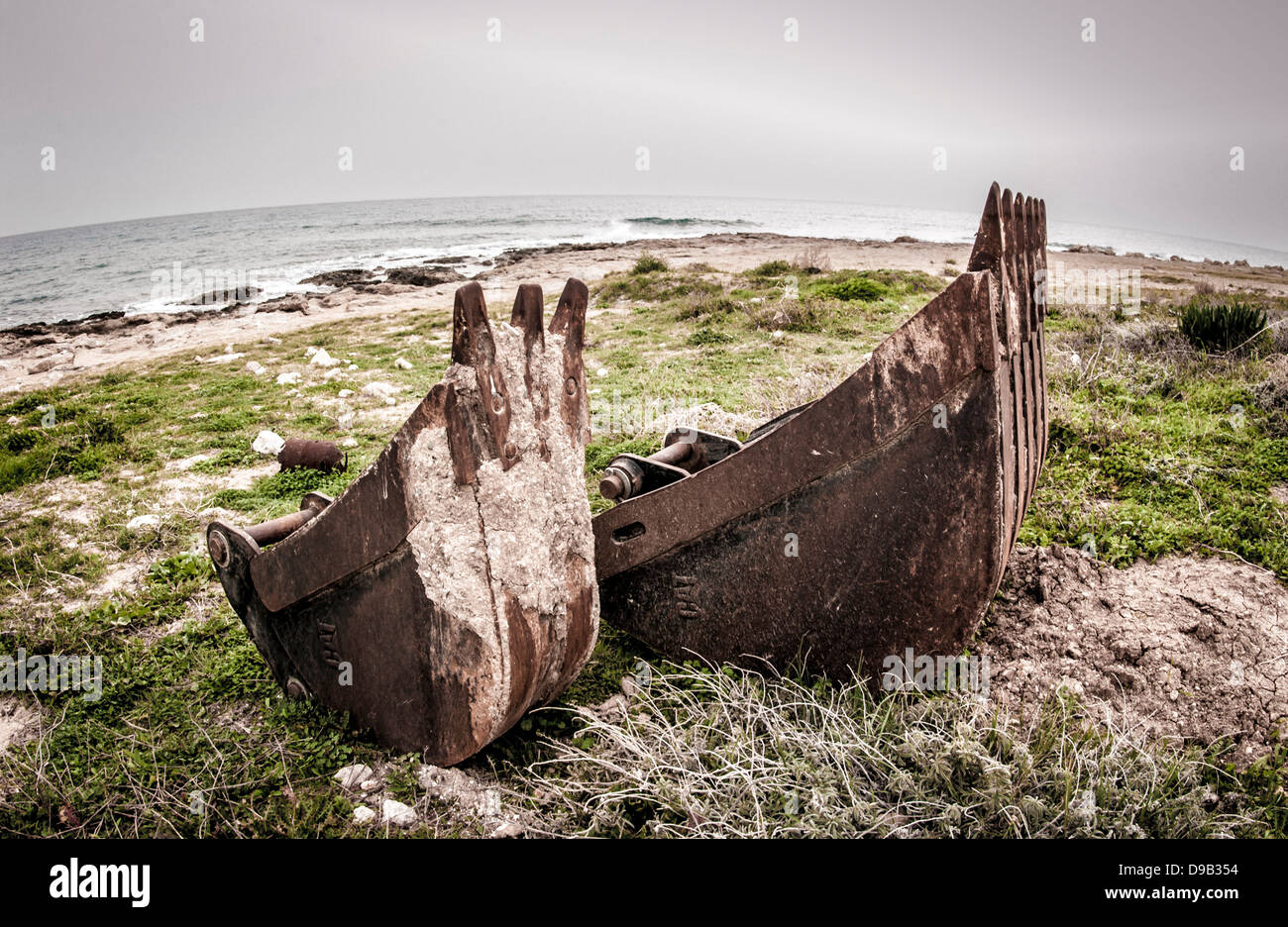 Rusty digger el cucharón en la playa en proyecto de construcción abandonados, Chipre Foto de stock