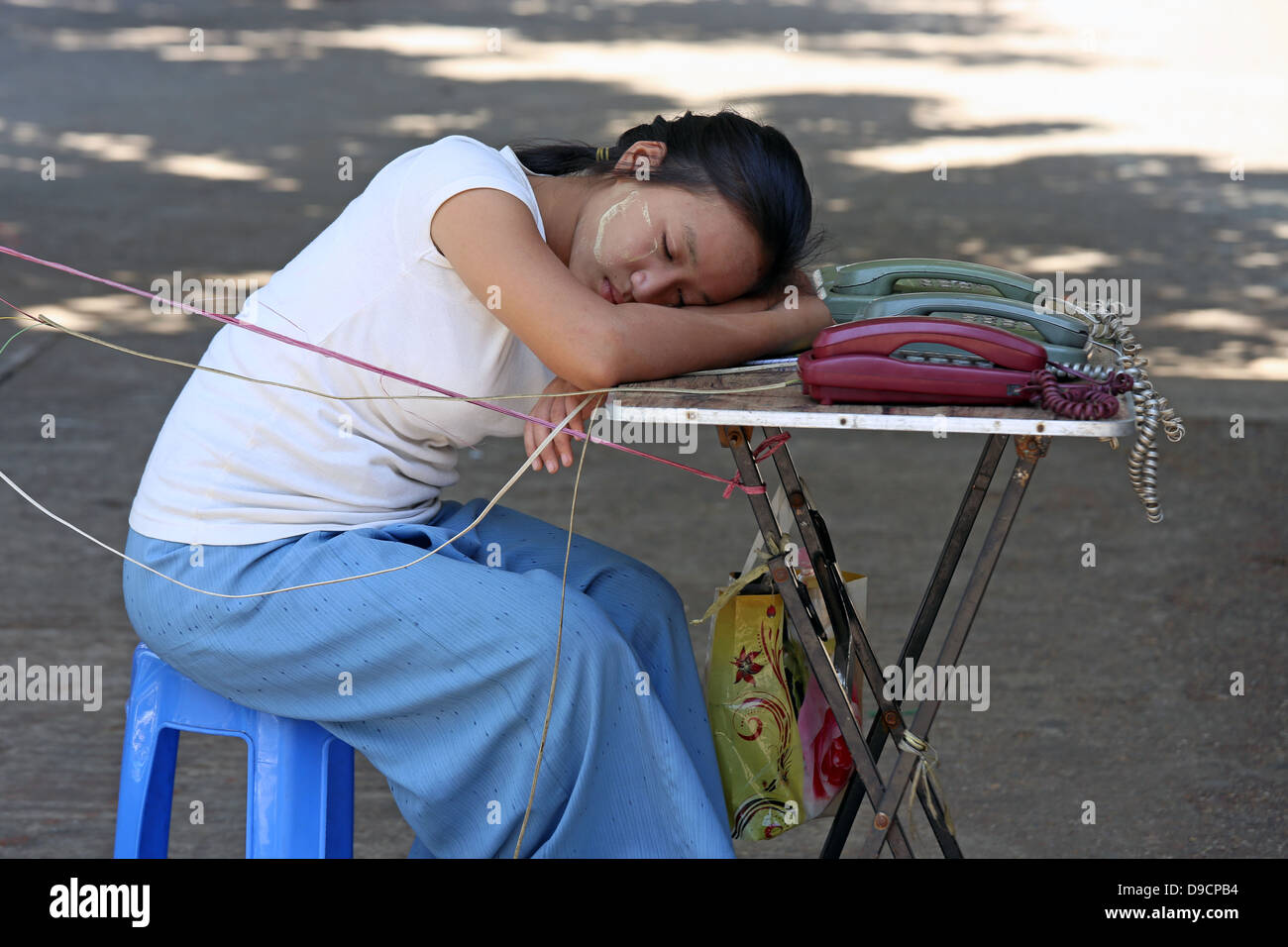 Las hembras jóvenes de operador telefónico dormido durante la presentación de tabla de teléfonos públicos en las calles de Yangon (Rangún) Myanmar, Sudeste de Asia Foto de stock
