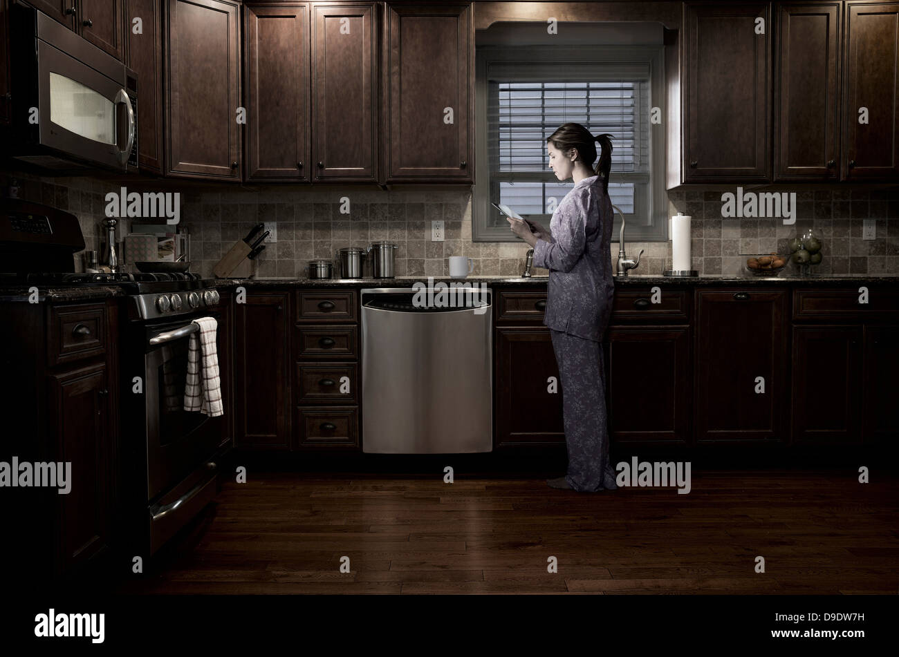 Mujer en la cocina de noche, mediante tableta digital Fotografía de stock -  Alamy