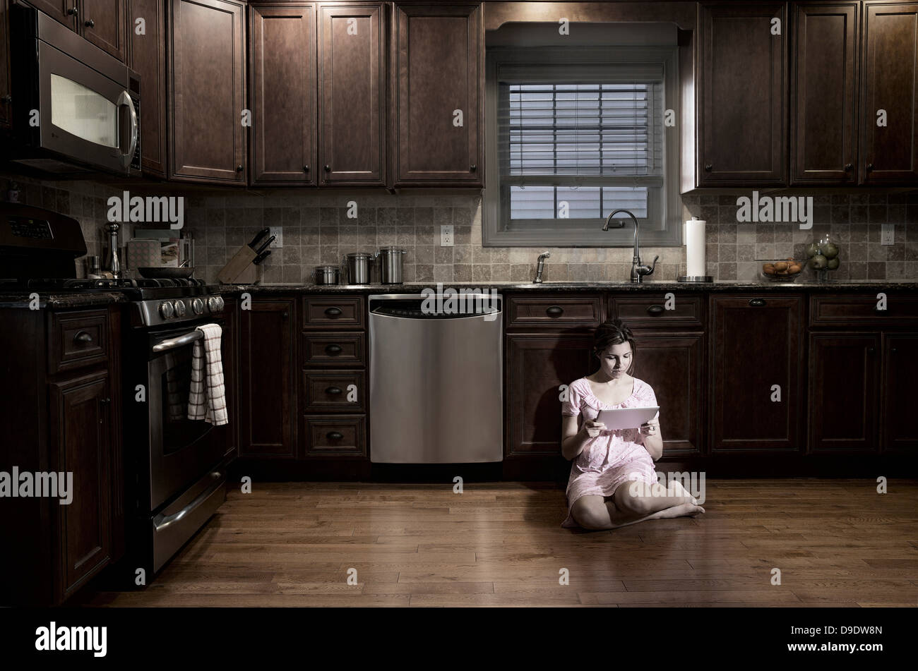 Mujer en la cocina de noche, mediante tableta digital Fotografía de stock - Alamy Mujer en la cocina de noche, mediante tableta digital Fotografía de stock - Alamy