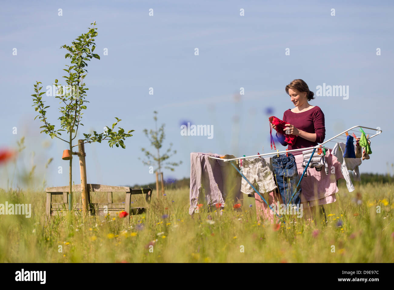 Mujer joven de colgar la ropa de lavandería en un caballo en un jardín rural Foto de stock