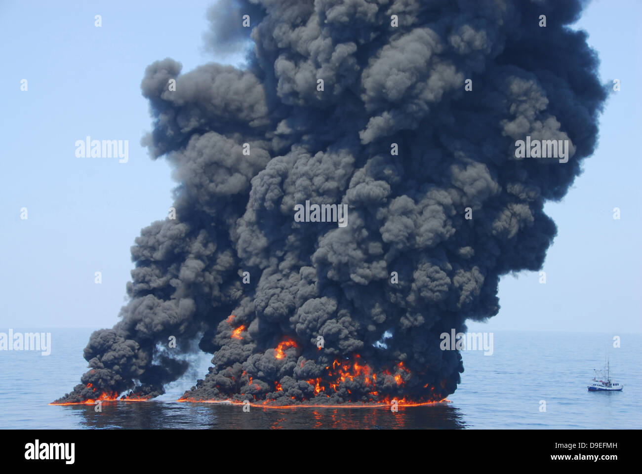 Nubes oscuras de humo y fuego emergen como aceite quemaduras durante un incendio controlado en el Golfo de México. Foto de stock