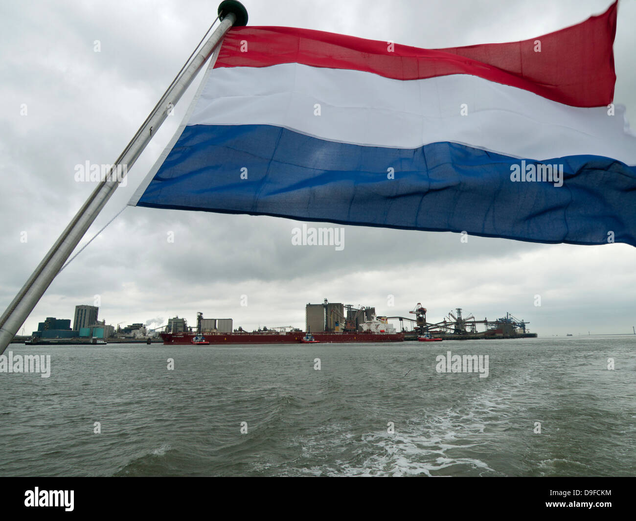 Ondear la bandera holandesa con una parte del puerto de Rotterdam, en