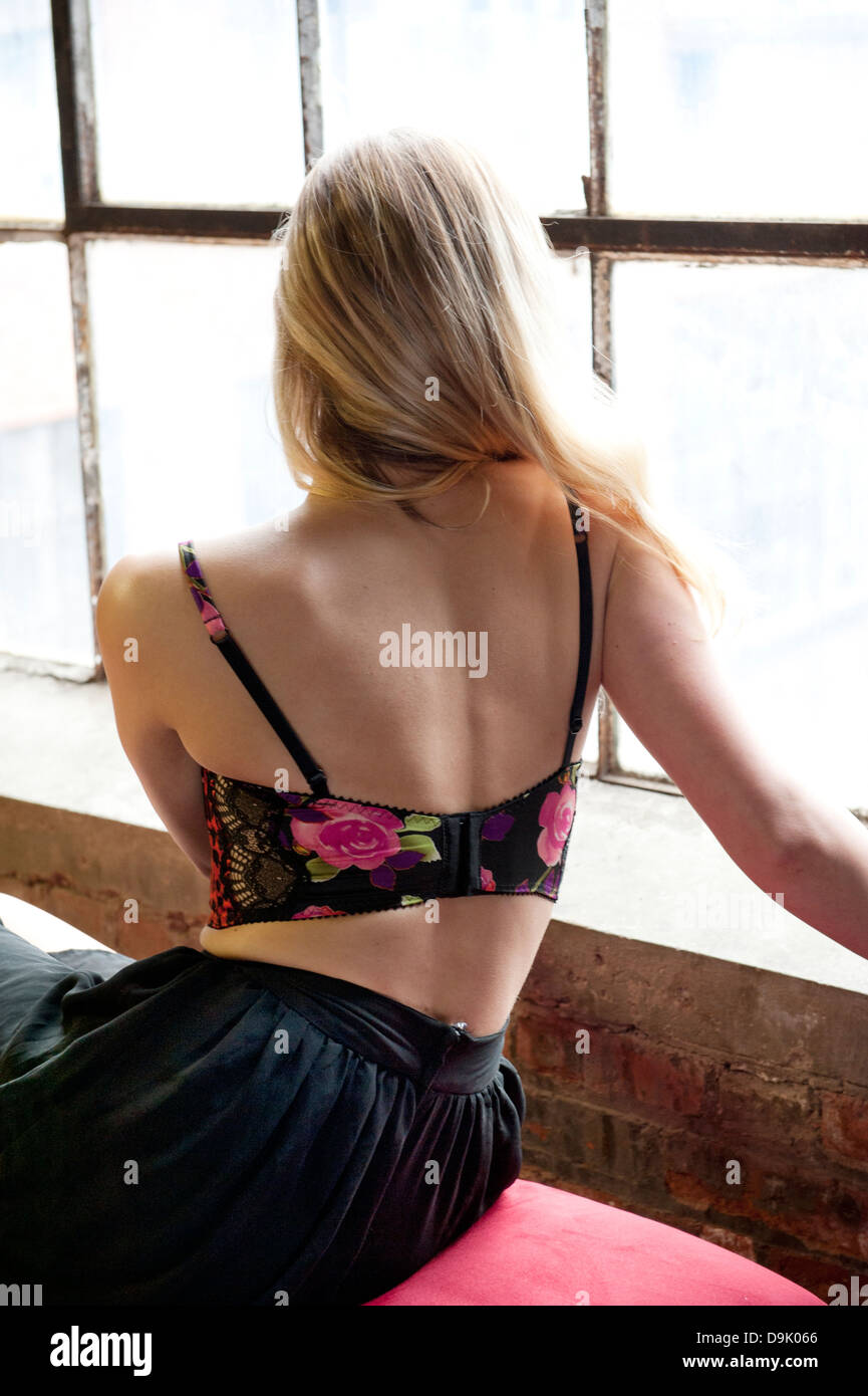 Joven y bella mujer rubia, usando lencería sexy, con la espalda mirando a  través de una ventana luminosa Fotografía de stock - Alamy