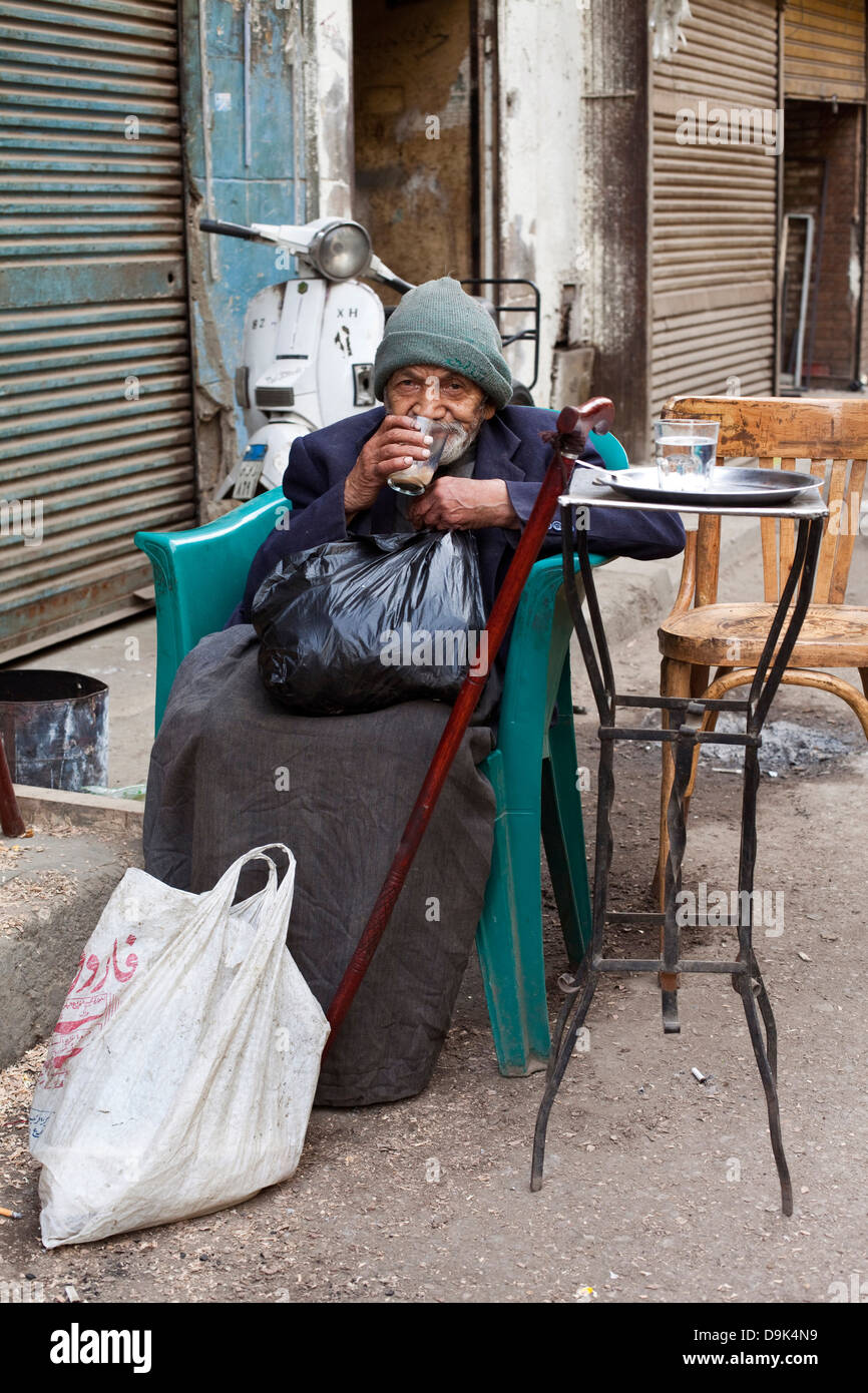 Un viejo hombre bebe una taza de té fuera de un café en el Bein al-Qasreen zona, Cairo islámico, El Cairo, Egipto Foto de stock