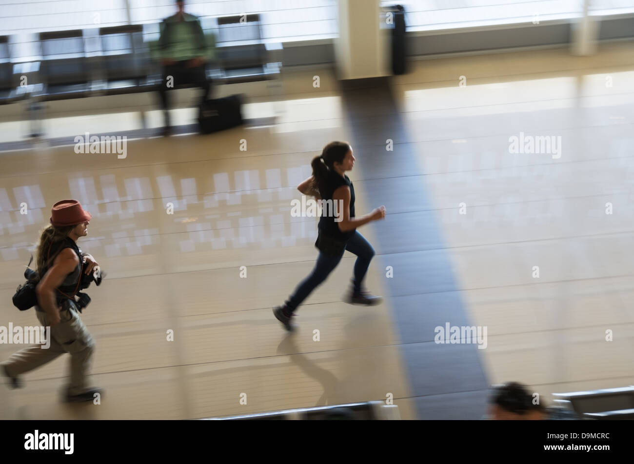 El hombre y la mujer ejecutando a través de un aeropuerto en una prisa para coger su vuelo Foto de stock